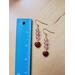 Light pink earrings lay on a table beside a ruler.  They measure approximately 2 and 1/8 inches long.